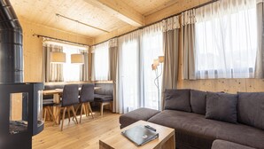 A cozy cabin interior with a wooden dining area, a sofa, and a fireplace. - Chalet With Spacious Terrace (Sankt Georgen am Kreischberg)
