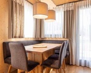 Enjoy meals in this cozy dining area with a wooden table and four chairs, surrounded by a large window and pendant lights.