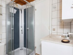 Bathroom features a glass-enclosed shower with handheld showerhead and wall-mounted faucet, a sink with soap dish and mirror.