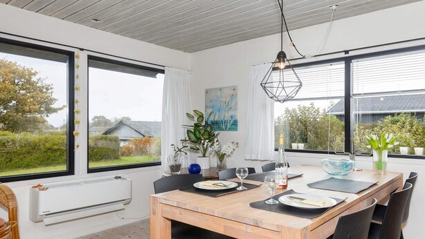 En matplats med ett träbord, svarta stolar och utsikt över omgivningarna genom stora fönster.
