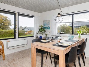 Enjoy meals in this dining area with a table for four, surrounded by large windows offering views of the surrounding greenery.