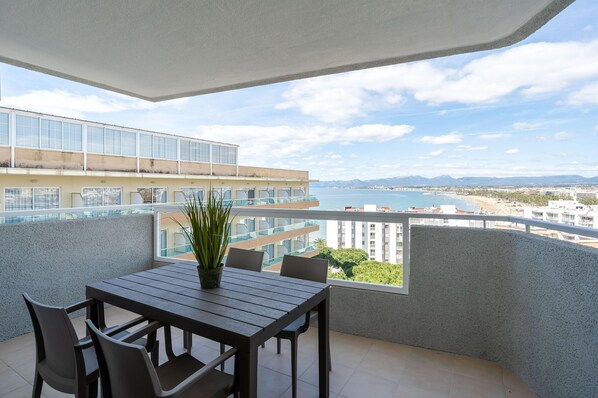 A balcony with a table and chairs, overlooking a cityscape and the sea. - Chic Stay by the Beach (Cambrils)