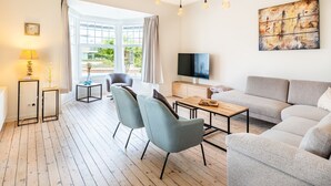 A modern living room with a sofa, chairs, a TV, and a painting on the wall. - Villa in Koksijde Near the Sea (Koksijde)
