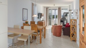 A modern living room with a dining area, a fireplace, and a balcony with a view. - Appartement im Ferienpark in Rechlin (Rechlin)