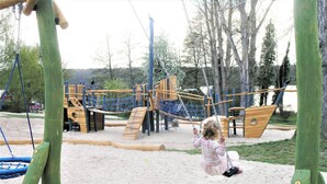 A playground with a swing set, climbing structures, and a sandy play area. - Ferienwohnung im Aparthotel Seepanorama (Mirow)