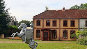 A building labeled "HAUS OLIVER" with a statue of a horse and rider in front. - Ferienhaus Oliver, Wendorf (Kuhlen-Wendorf)