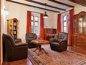 A room with two leather chairs, a wooden table, a piano, and a large wooden cabinet. - Ferienhaus Oliver, Wendorf (Kuhlen-Wendorf)