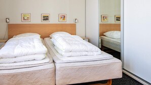 A hotel room with two single beds, a wooden headboard, and three framed pictures on the wall. - 4 Person Holiday Home on a Holiday Park in Hejls (Hejls)