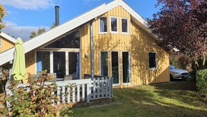 A two-story wooden house with a sloped roof, large windows, and a visible chimney. - Exklusives Skandinavisches Ferienhaus (Mirow)