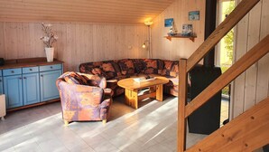 A cozy cabin interior with a wooden ceiling, a blue cabinet, a patterned sofa, and a wooden table. - Exklusives Skandinavisches Ferienhaus (Mirow)