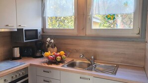 A compact kitchen with a microwave, sink, and a bowl of fruit on the counter. - Exklusives Skandinavisches Ferienhaus (Mirow)