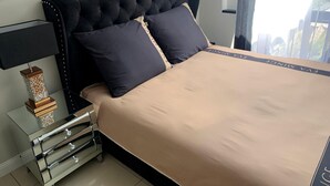 A neatly made bed with a black headboard, a beige bedspread, and two dark pillows. - Holiday Home in Miedzyzdroje for 8 Persons (Miedzyzdroje)