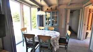 Un coin repas comprenant une table ronde, quatre chaises et un buffet aux portes vitrées.