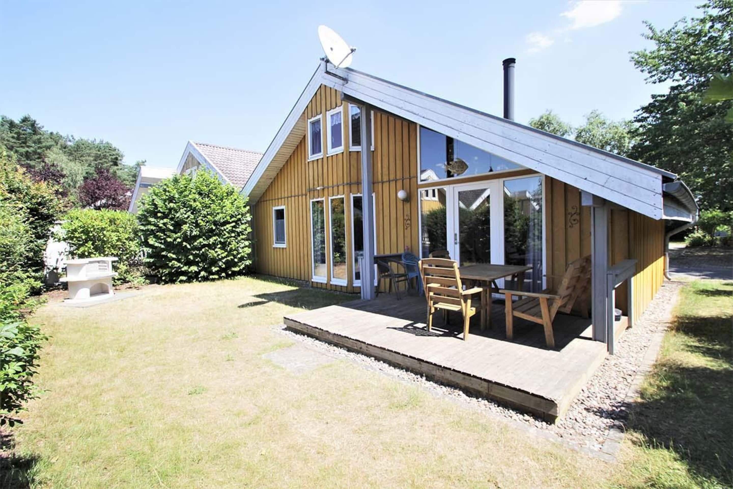 Ein Holzhaus mit Terrasse, Satellitenschüssel und Schornstein.