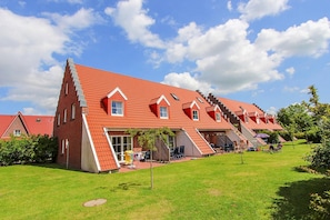 A red-roofed building with multiple levels, a grassy yard, and outdoor seating areas. - Seepark Burhave, Burhave (Butjadingen)