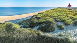 A beach with a dune and a red structure on top. - Apartment in Holiday Park in Vederso Klit (Ulfborg)