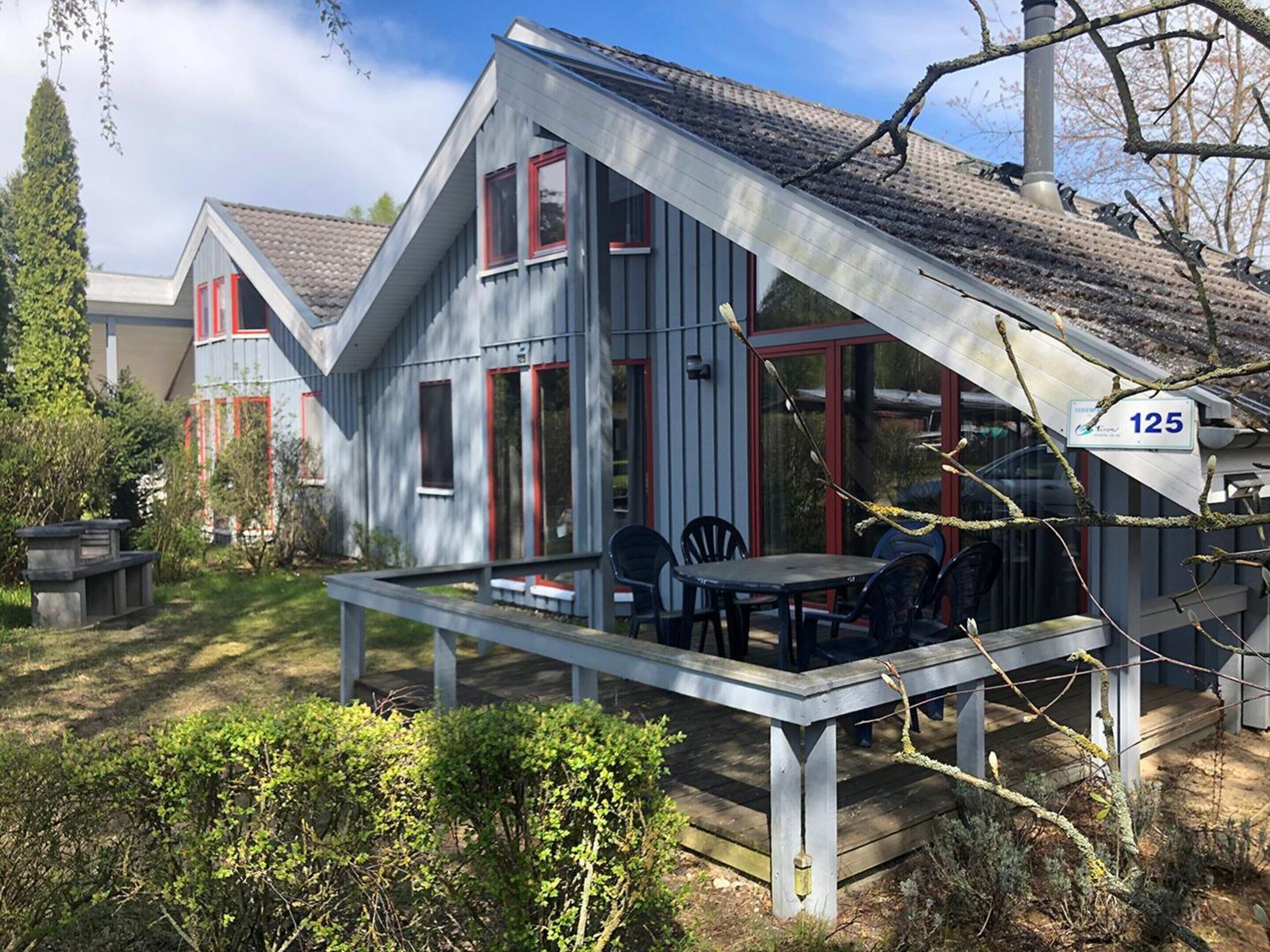 A house with a sloped roof, a porch with outdoor seating, and a visible house number 125.