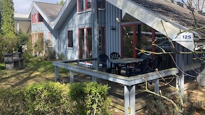 A house with a sloped roof, a porch with outdoor seating, and a visible house number 125. - Ferienhaus im Skandinavischen Stil (Mirow)