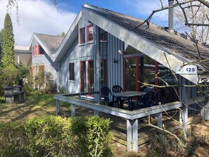 A house with a covered patio, a number '125' sign, and a small garden area. - Ferienhaus im Skandinavischen Stil (Mirow)