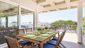 A covered outdoor dining area with a table set for four, surrounded by wooden chairs with blue cushions. - Villa Primasol by Villa Plus (Punta Prima)