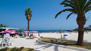 A beachside restaurant with outdoor seating and palm trees. - Villa Primasol by Villa Plus (Punta Prima)