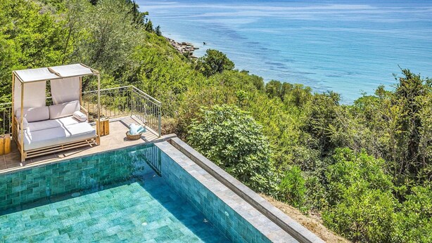 A poolside area with a cushioned seating arrangement overlooking a clear blue sea. - Villa Kalou Cottage by Villa Plus (Ionian Islands)