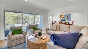 Ein geräumiges Wohnzimmer mit einem großen Sofa, zwei Sesseln, einem Couchtisch und einem Essbereich mit Stühlen und Tisch.