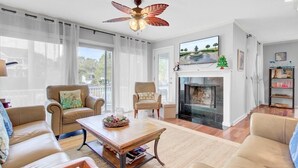 Ein Wohnzimmer mit Kamin, zwei Sesseln, einem Couchtisch und einem Deckenventilator.