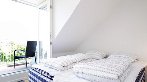 A bedroom with a bed, a chair, and a view of the outdoors. - 6 Person Holiday Home on a Holiday Park (Karrebæksminde)