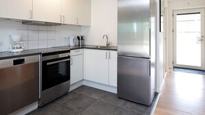 A modern kitchen with white cabinets, stainless steel appliances, and a large refrigerator. - 6 Person Holiday Home on a Holiday Park (Karrebæksminde)