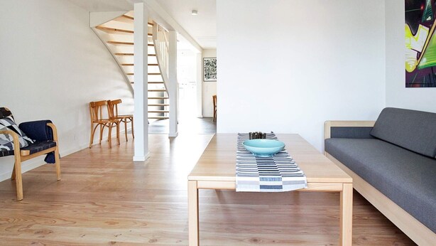 A modern living room with a wooden floor, a sofa, a coffee table, and a staircase leading to another room. - 6 Person Holiday Home on a Holiday Park (Karrebæksminde)