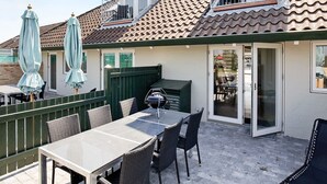 A patio area with a table and chairs, a barbecue grill, and umbrellas. - 6 Person Holiday Home on a Holiday Park (Karrebæksminde)