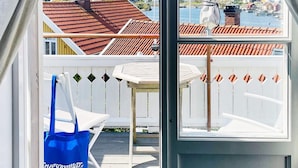 Udsigt fra et værelse med et vindue, der kigger ud over en træterrasse og en havn.