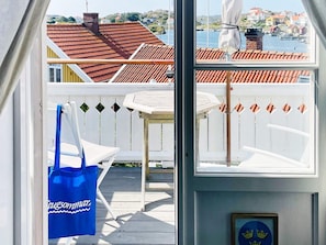 Vista desde una habitación con ventana que da a una terraza de madera y un puerto.