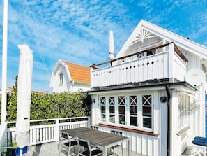 A white building with a balcony, a table, and chairs. - 4 Star Holiday Home in Kyrkesund (Kyrkesund)