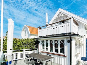 A white building with a balcony, a table, and chairs outside.