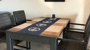 A dining area with a table, chairs, a pendant light, and a sunset painting on the wall. - Appartement im Ferienpark in Rechlin (Rechlin)