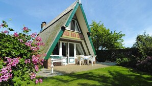 Una casa con techo empinado, una chimenea de ladrillo y un amplio ventanal corredera.