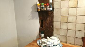A wooden table with a tea set and spice rack against a wall with a wooden texture.