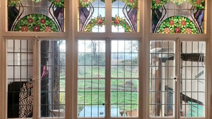 A set of stained glass doors with floral designs and a view of a garden. - Historic half-timbered house, sauna, natural garden, fitness, movie theater, view  (Detmold)