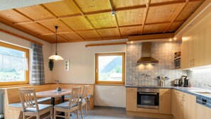 Una cocina moderna con armarios de madera, horno empotrado y un amplio ventanal con vistas a un paisaje montañoso.