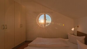 Ein Schlafzimmer mit Dachfenster, einem Bett und einem Kleiderschrank.