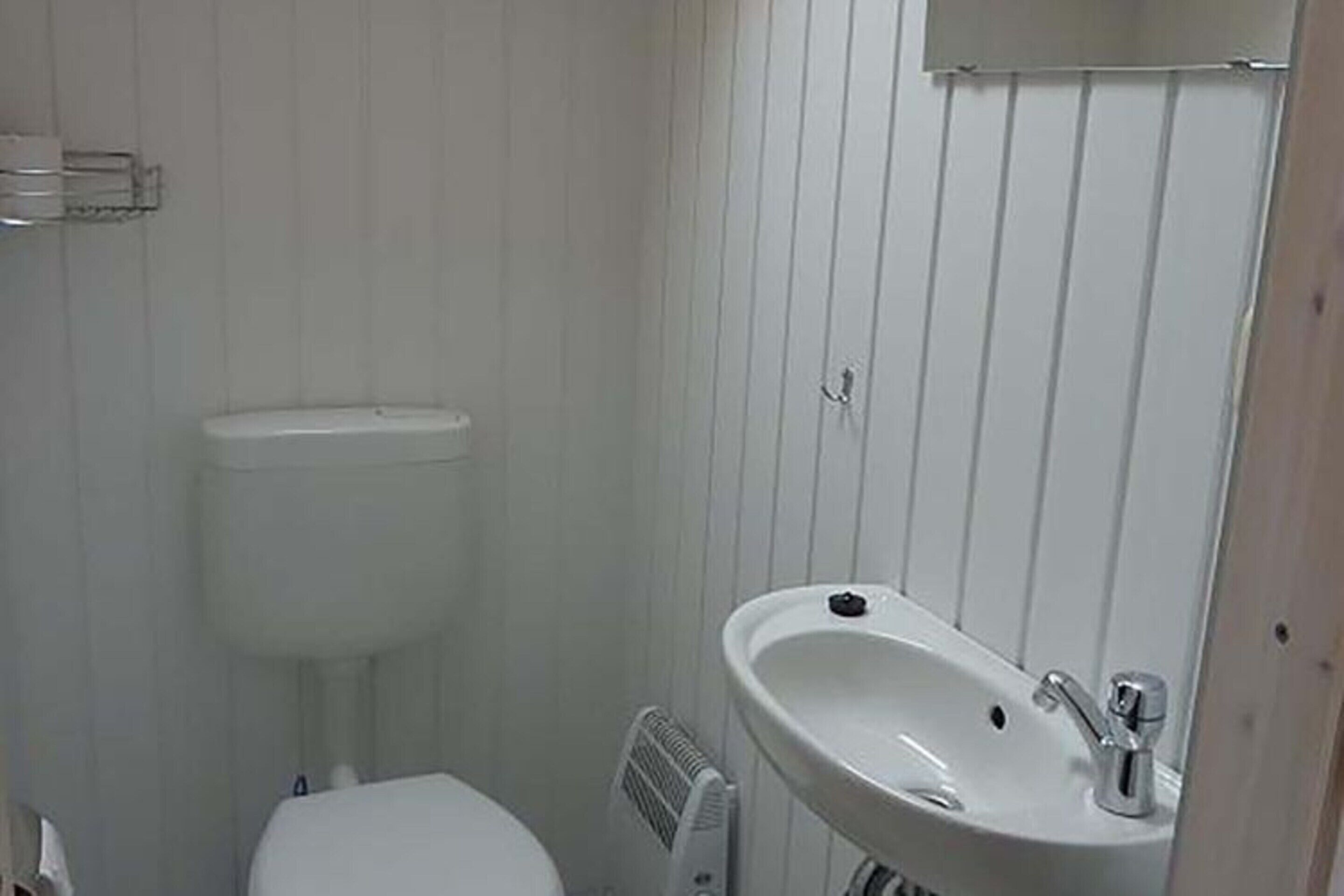 Egy kis fürdőszoba, amelyben WC, lábazatos mosdókagyló és radiátor található.