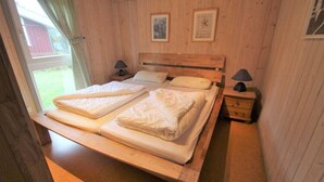 Une chambre à coucher aux murs lambrissés, avec un lit, deux tables de chevet et une fenêtre.