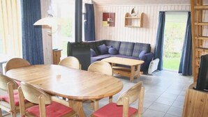 Ein gemütliches Zimmer mit einem Holzesstisch, Stühlen, einer Couch und einem Fernseher.