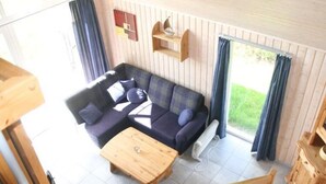 Ein Zimmer mit Ecksofa, Couchtisch aus Holz, Heizkörper und Blick auf Grünflächen.