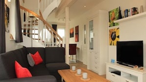 A modern living room with a sofa, coffee table, and TV stand. - Liebevoll Eingerichtetes Appartement (Rechlin)