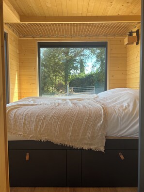 Enjoy a peaceful retreat with a large window offering a view of the outdoors, a comfortable bed, and a stylish design.