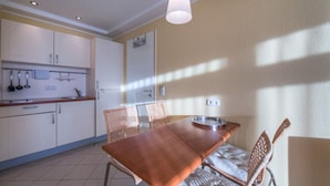A kitchen with a dining table and chairs, a hanging light fixture, and cabinets. - Apartment in Granzow Near the Lake (Mirow)