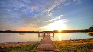A wooden pier extending into a calm lake with a sunset in the background. - Apartment in Granzow Near the Lake (Mirow)